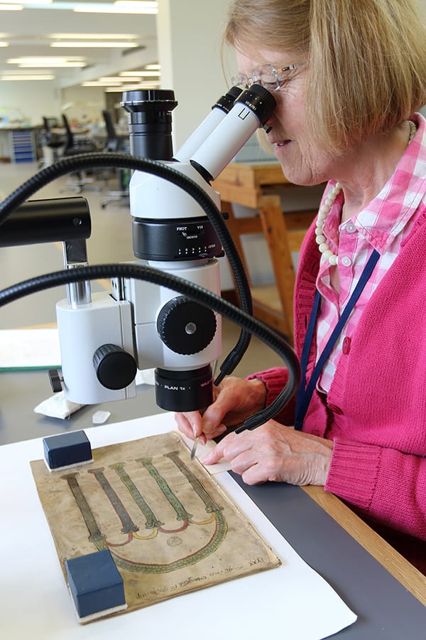 Sabina Pugh removing glue from folio 1 under the microscope